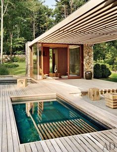 an outdoor swimming pool surrounded by greenery and wooden structure with steps leading up to it