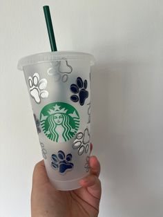 the starbucks cup has paw prints on it and is being held up by a hand