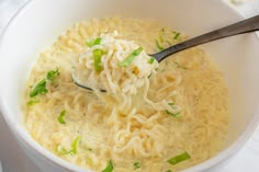 a white bowl filled with noodles and green onions