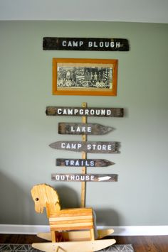 a wooden rocking horse sitting in front of a wall with signs on it's sides