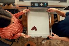 two people holding up an open box with red hearts on it