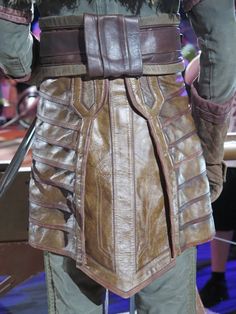 the back of a man's brown leather armor with metal straps and buckles