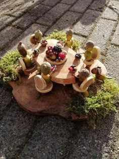 a wooden table topped with lots of fruit on top of a stone floor covered in grass