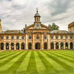 a large building with a clock on the top of it's tower and grass in front