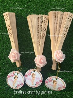 three wooden fans with pink flowers on them and tags attached to the handles for each fan