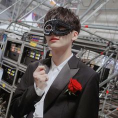 a man in a suit and mask holding a rose