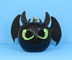 a halloween pumpkin with black wings and green eyes on a blue background, for decoration