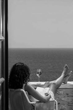 a woman sitting in a chair on top of a balcony next to the ocean