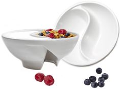 a bowl with cereal and berries in it next to another bowl that has blueberries and raspberries