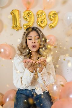 a woman standing in front of balloons and confetti with the number 999 on it