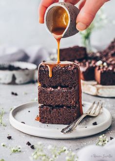 someone drizzling caramel on top of a piece of chocolate brownie