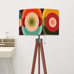 a lamp that is on top of a wooden tripod next to a white table