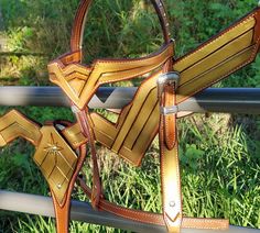 a close up of a horse's bridle on a rail in the grass