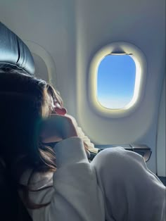 a woman sitting in an airplane looking out the window