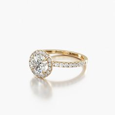 an engagement ring with a halo setting and pave set diamonds on the band, in yellow gold