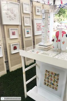 a table with pictures and vases on it in front of a wall full of framed photographs