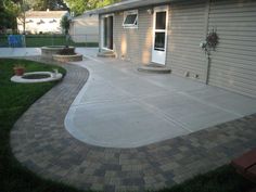 a concrete patio with brick pavers and steps leading up to the back door area