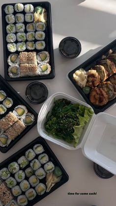 several trays filled with sushi and vegetables on top of a white countertop