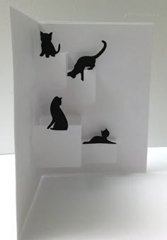 an open card with black cats on the front and bottom, sitting on white paper