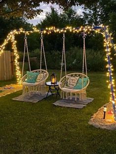 two white chairs sitting on top of a grass covered field next to a swing chair