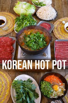 korean hot pot soup with vegetables and meats in bowls on a wooden table top