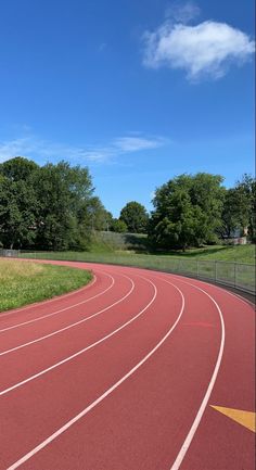 a running track in the middle of a field with trees and grass on both sides