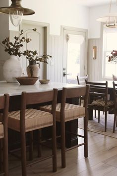 a dining room table with chairs and a vase on it