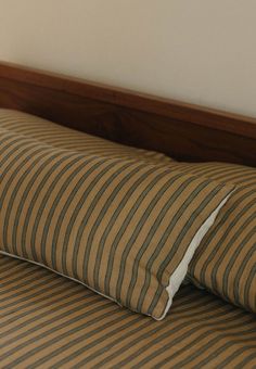 a striped pillow on top of a bed with a wooden headboard and night stand