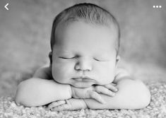 a black and white photo of a baby sleeping with his hands on his chins