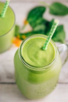 two glasses filled with green smoothie sitting next to each other