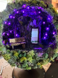 a fake tree with purple lights and a bench in the middle is shown on top of a table