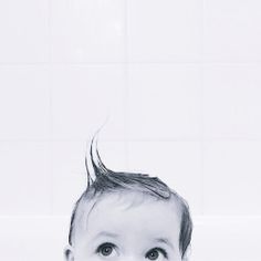 a black and white photo of a baby in the bathtub with his hair blown back