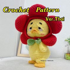 a crochet chicken with a red hat and green bow tie standing in front of a frame