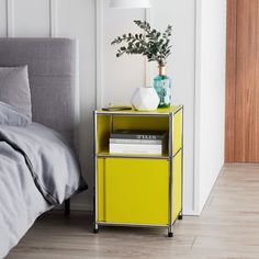 a yellow nightstand with books on it next to a bed