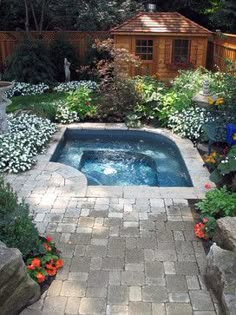 an outdoor hot tub surrounded by flowers and trees