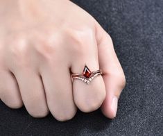 a woman's hand wearing a ring with a red stone on the middle finger