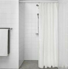 a white shower curtain in a bathroom next to a bathtub and toilet paper roll