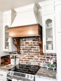 a kitchen with an oven, stove and counter top in white cabinets next to a brick wall