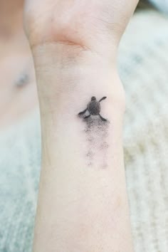 a person with a small tattoo on their wrist that has an image of a bird flying in the sky