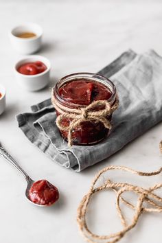 a jar filled with jam sitting on top of a table next to two spoons