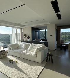 a living room filled with white furniture and large windows