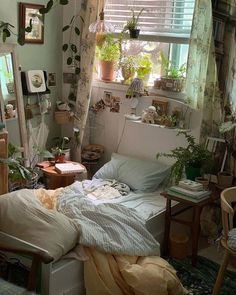 a messy bedroom with plants on the windowsill