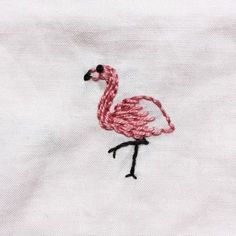 a pink flamingo embroidered onto a white shirt