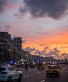 cars are driving down the street at sunset