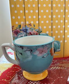 a tea cup sitting on top of a table next to a yellow and white polka dot wall