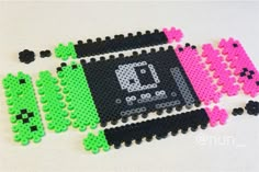 an image of some pixel art made out of plastic beads on a white table with pink and green decorations