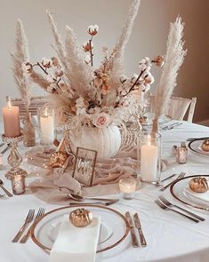 a table set with plates, silverware and candles