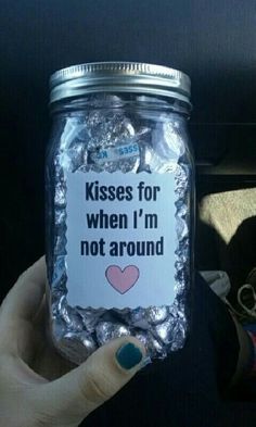 someone is holding up a jar with some candy in it that says kisses for when i'm not around