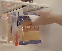 a person reaching for some food on the shelf in front of him and holding it up