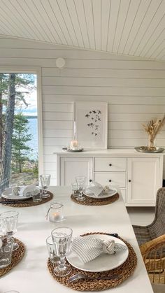 a dining room table with place settings and plates on it, along with wicker chairs